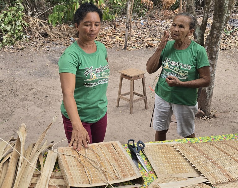 Two women participating in the program show crafts made from straw